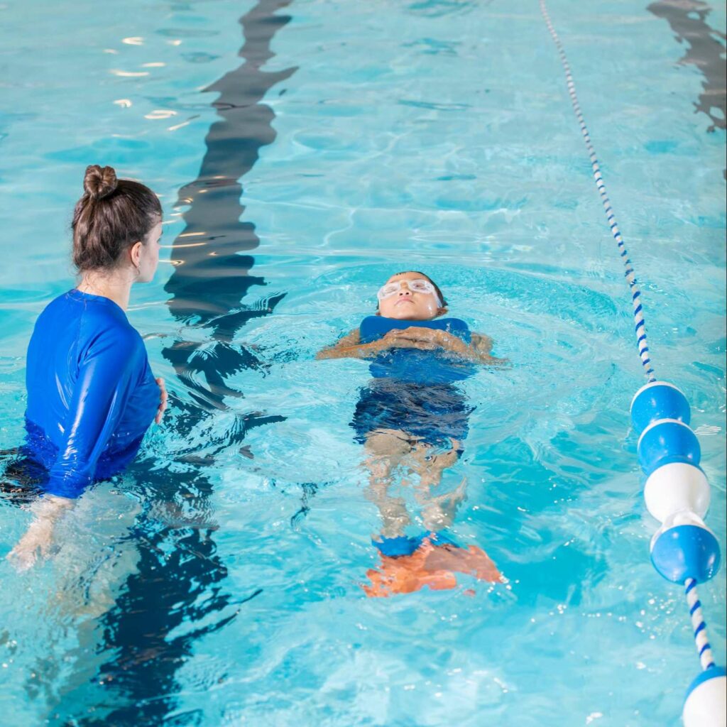 un enfant prend des cours de natation avec un maitre nageur.